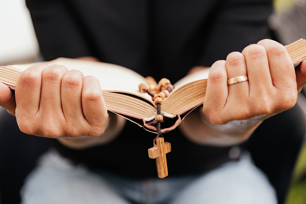 Close-Up Shot of a Person Reading a Book with Rosary